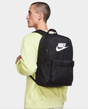 Person wearing a black Nike backpack on a light gray background